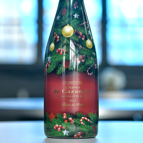 Zoom sur une bouteille de champagne Charles de Cazanove Happy Holidays 1, bouteille qui est décorée et s’apparente à un sapin de Noël / Close-up of a bottle of Charles de Cazanove Happy Holidays 1 champagne, decorated to resemble a Christmas tree.