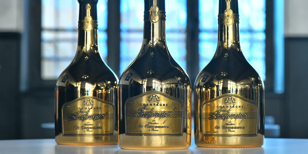 3 bouteilles de Stradivarius Gold alignées sur une table / 3 bottles of Stradivarius Gold lined up on a table